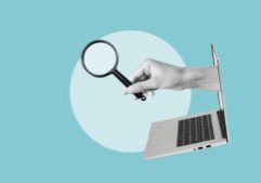 A hand holding a magnifying glass emerges from an open laptop screen against a blue background with a large white circle.